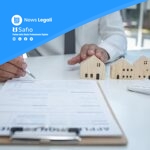 Professionista immobiliare con modellini case e documenti contrattuali su scrivania