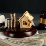 Martello giudice con casa in legno e monete su banconote per controversie immobiliari e diritto successorio