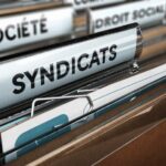 Cartella archivio con etichetta "SYNDICATS" in primo piano, rappresentante documentazione sindacale e diritti dei lavor…