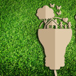 Spina elettrica con casa e presa su sfondo verde simboleggia efficienza energetica e sostenibilità ambientale