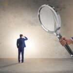 Uomo d'affari osservato da lente d'ingrandimento simboleggia controllo legale e compliance normativa