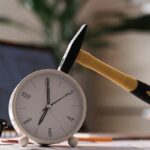 Orologio da tavolo con martello e occhiali su scrivania, simbolo di scadenze e termini legali