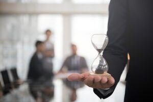 Professionista con clessidra in mano rappresenta scadenze e termini nella divisione ereditaria e tassazione dell'atto