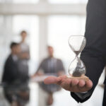 Professionista tiene clessidra nel pugno rappresentando il tempo nella cessione quote sociali e patti di famiglia