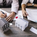 Consulente legale analizza documenti mutuo con modelli casa e calcolatrice
