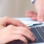 Mani che digitano su tastiera laptop durante consultazione legale online