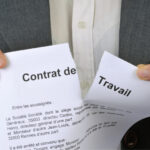Persona in abito formale strappa contratto di lavoro francese durante discussione legale o controversia occupazionale