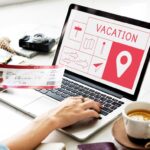 Persona prenota vacanza online con biglietto aereo e laptop mostrando mappa destinazione viaggio