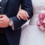 Sposi con anelli nuziali e bouquet rosa, dettagli di cerimonia matrimoniale per contratto prematrimoniale