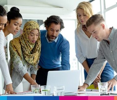 associazione-cult-2-22 Gruppo di professionisti multietnici riuniti attorno a un laptop durante una riunione di lavoro collaborativa in ufficio