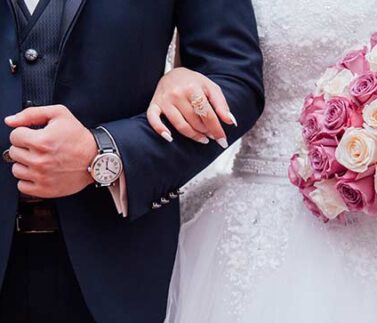 Sposi mostrano anelli matrimoniali e bouquet rosa in cerimonia nuziale con contratto prematrimoniale