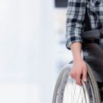 Persona disabile sulla sedia a rotelle afferra la ruota, primo piano della mano
