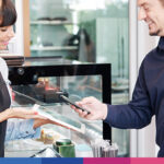 Consulente fiscale spiega vantaggi carta fedeltà ristorante a cliente durante transazione