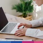 Donna professionista al lavoro al computer portatile in ufficio con documenti e pianta
