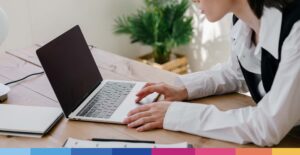 Donna professionista al lavoro al computer portatile in ufficio con documenti e pianta