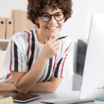 Donna consulente con occhiali al lavoro davanti a computer in ufficio moderno
