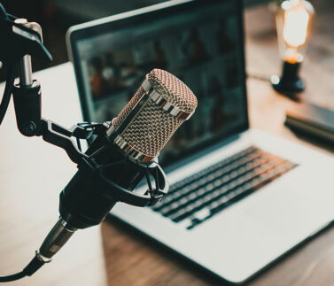 Studio di registrazione podcast con microfono professionale e laptop per contenuti legali e fiscali