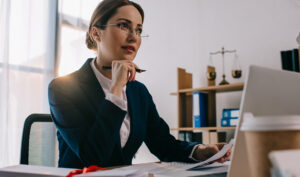 Avvocato donna in studio legale al lavoro su documenti e laptop per redazione atti processuali