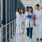 Team di giovani medici specialisti in corridoio ospedaliero con cartella clinica