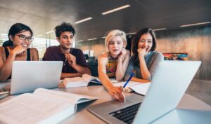 Giovani professionisti in riunione di lavoro collaborativo con laptop e documenti