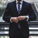 Professionista legale in abito formale ajusta la cravatta blu davanti a edificio moderno