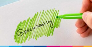Mano che evidenzia con pennarello verde la scritta "Green Washing" su carta bianca, simbolo della pratica ingannevole d…