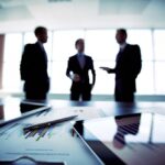 Riunione di professionisti e manager in ufficio con grafici economici e documenti legali sul tavolo