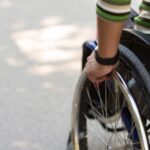 Persona disabile su sedia a rotelle con assistenza sanitaria, tema diritti e tutela legale pazienti